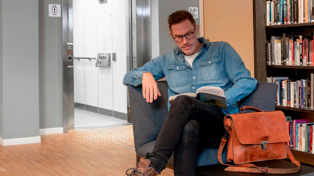 Man reading book in sofa in front of lift